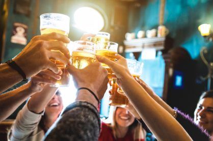 Group of happy friends drinking and toasting beer